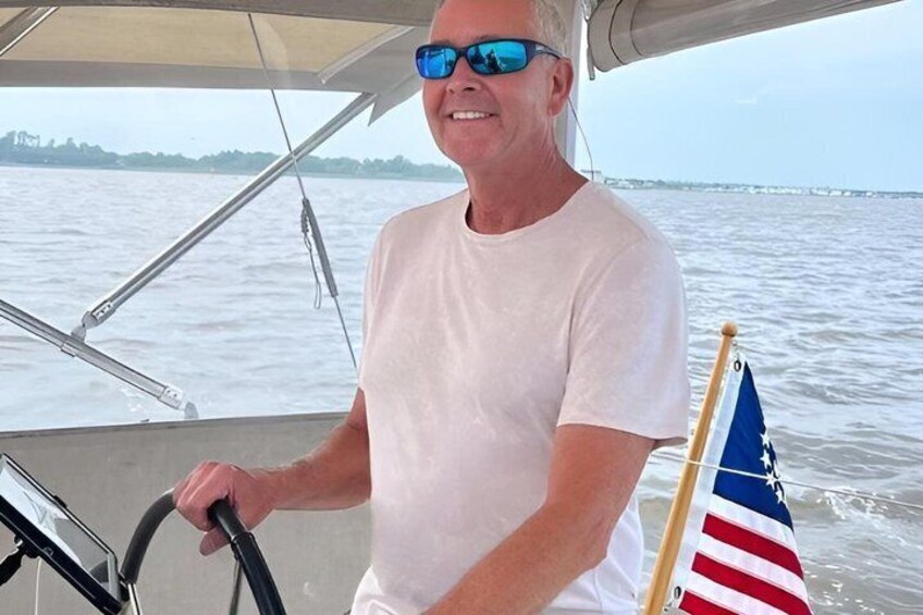 A person steering a boat with an American flag on the bow. 2