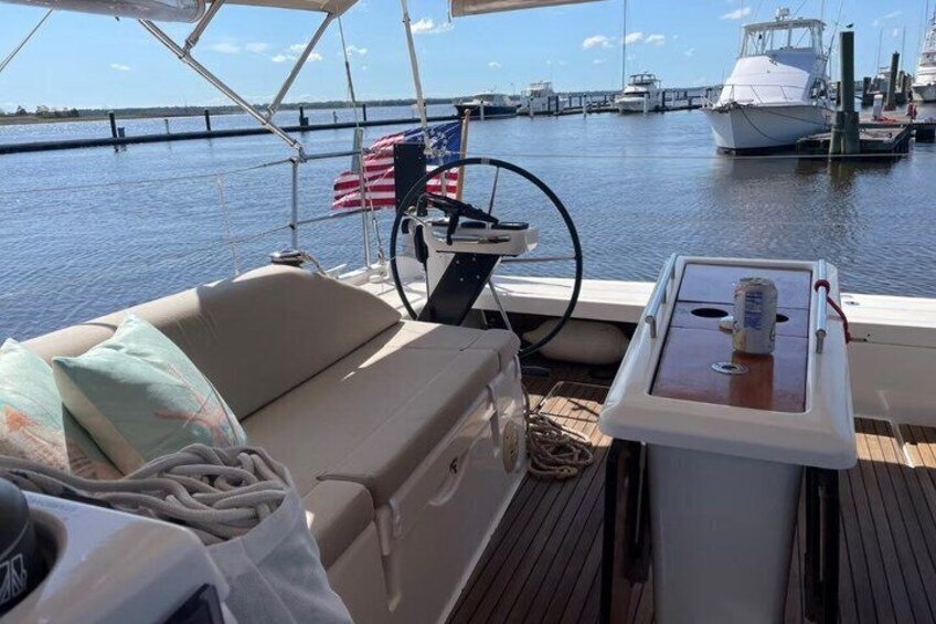 A boat deck with a cushioned seating area, a small table with a can, and a flag. 2