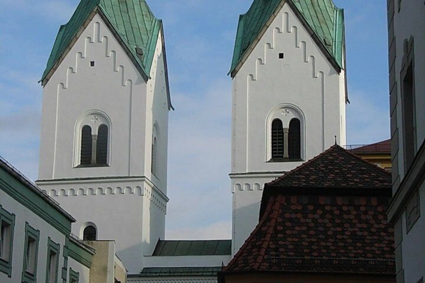 Two white church towers with green roofs and arched windows. 2