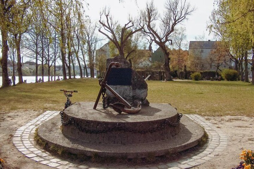 A sculpture of a horse and rider in a park with a pond and trees in the background. 3