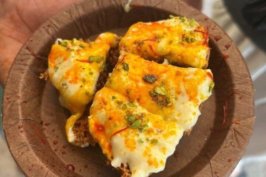 A plate of food with melted cheese and green herbs. 5