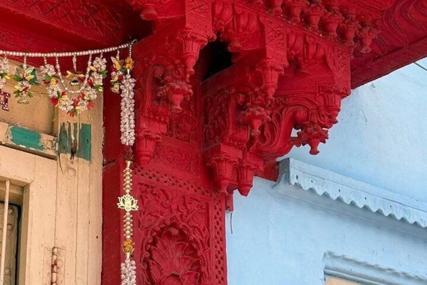 A red architectural structure with intricate carvings and a white wall. 2
