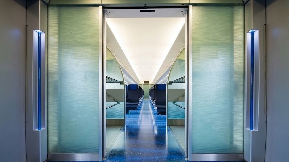 A modern elevator shaft with glass doors and a blue-lit interior. 4