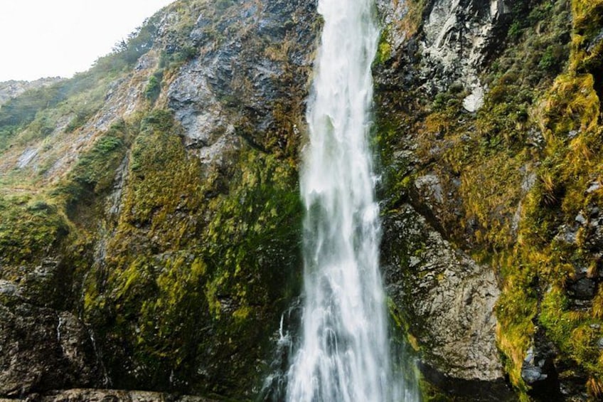 A waterfall cascading down a rocky cliff with lush greenery. 3
