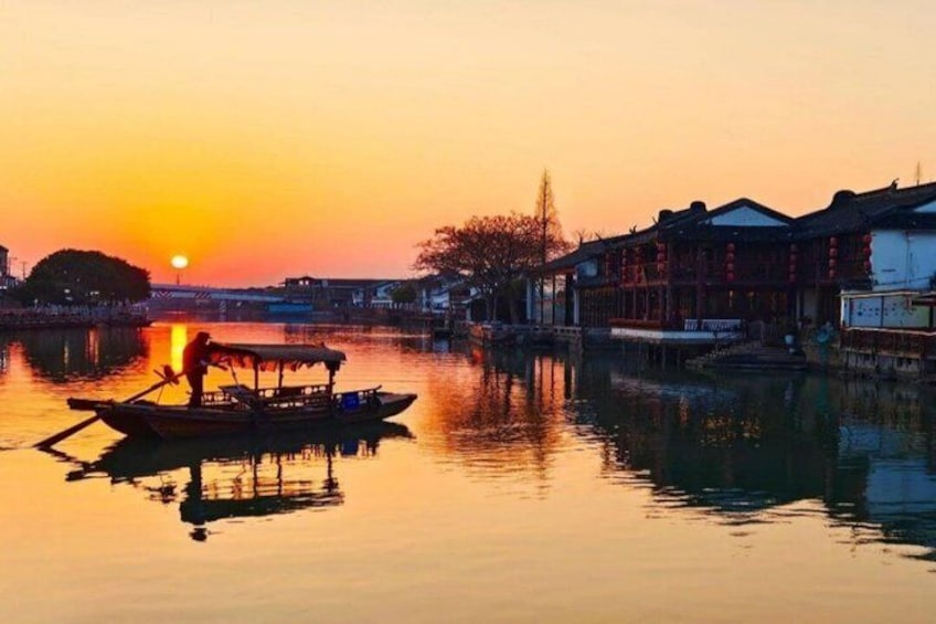 A sunset over a calm river with traditional buildings on the right bank. 1