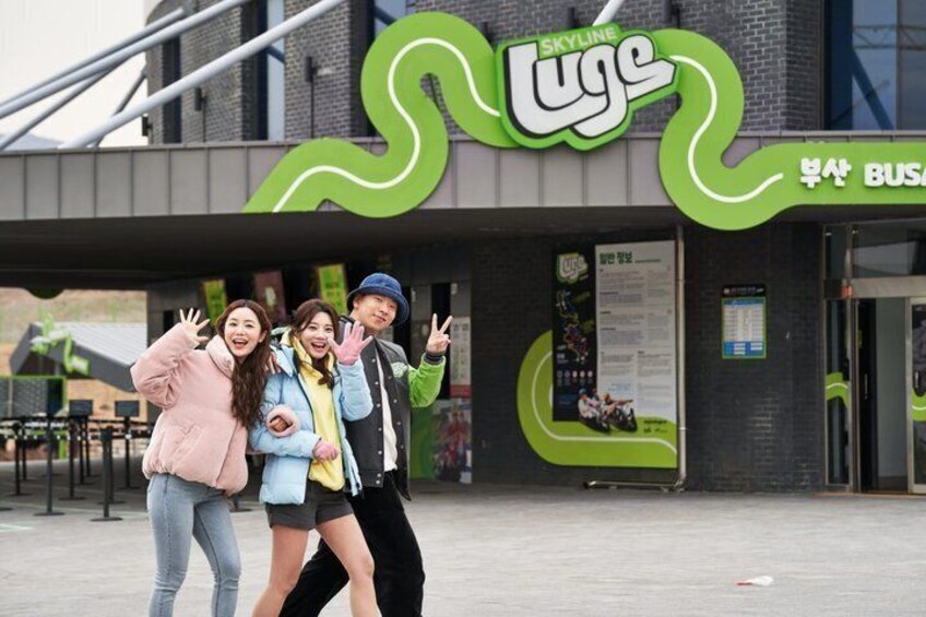 A building with a green and white logo, a sign reading 'BUSA BUSA,' and a few people posing in front. 5