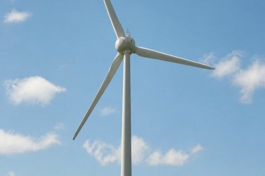 A wind turbine against a clear blue sky with scattered clouds. 3