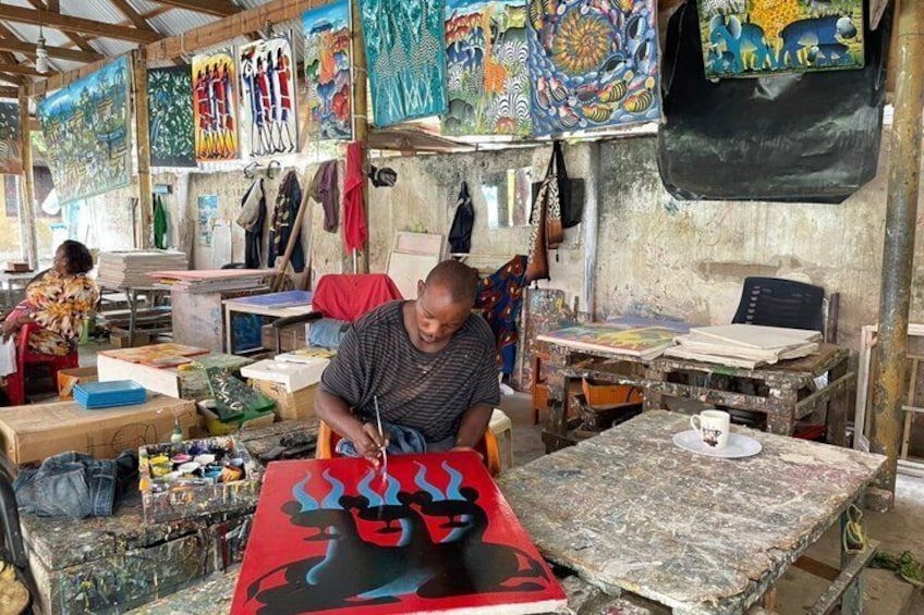 A person painting on a canvas in a workshop with various artworks and tools around. 2