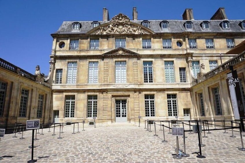 A historic building with a cobblestone courtyard, large windows, and a central entrance. 3