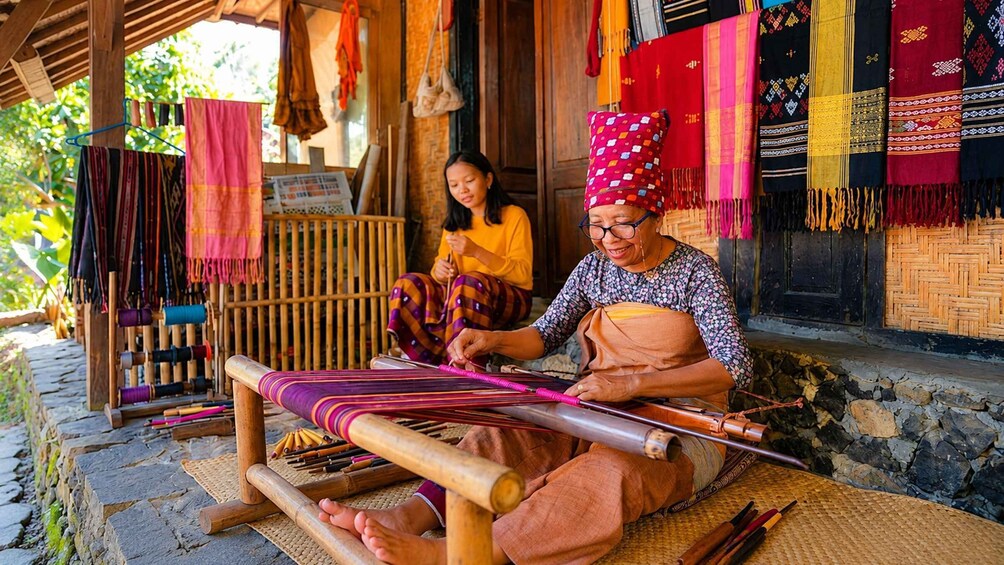Two individuals engaged in weaving with traditional tools and colorful textiles. 4