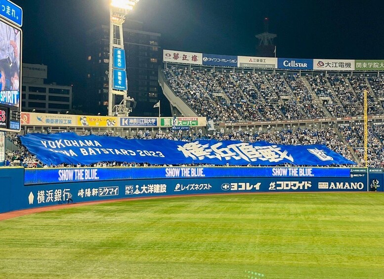 A baseball stadium at night with a large blue banner. 5