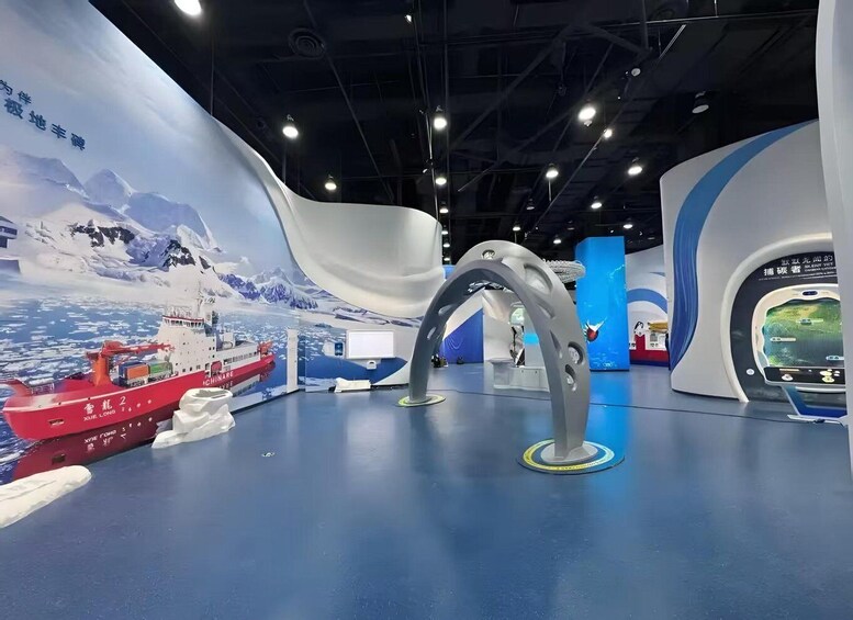 A maritime exhibit with a model ship, a large mural of a snowy landscape, and a futuristic-looking structure. 3