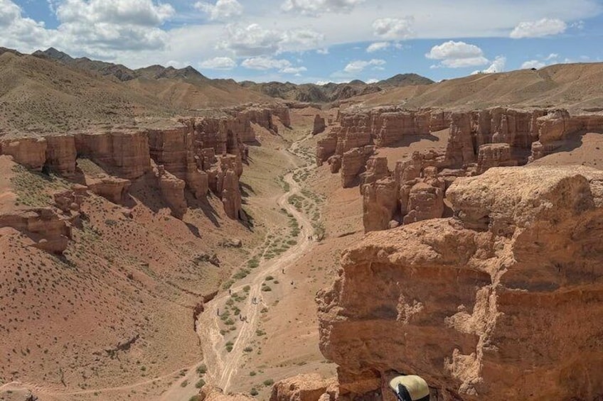 A canyon with layered rock formations and a winding path. 5