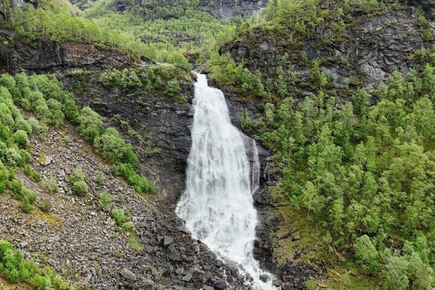A waterfall cascading down a rocky cliff surrounded by lush greenery. 4