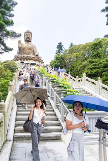 A large Buddha statue at the top of a staircase surrounded by lush greenery. 2