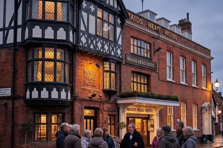 A historic building with the sign 'Maids Head Hotel' and a group of people standing in front. 4