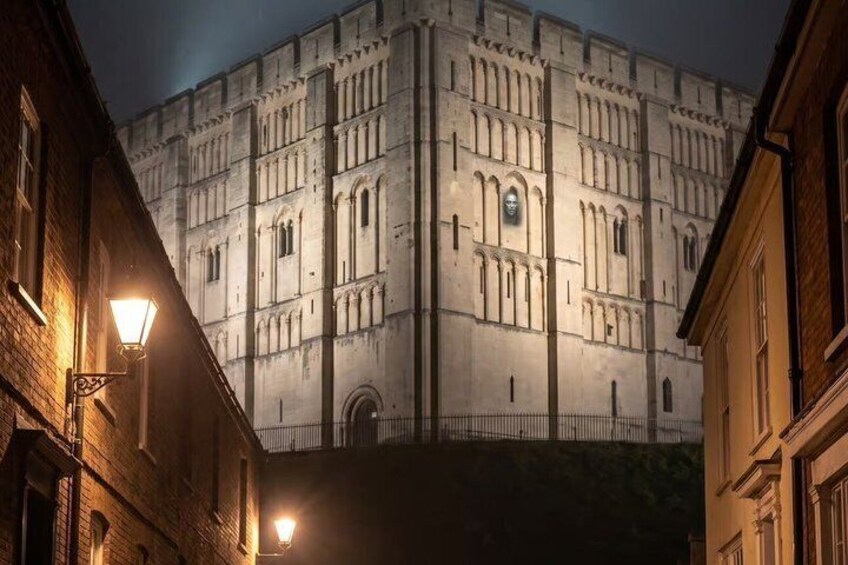 A historic building with arched windows and a central entrance, illuminated by street lamps. 1