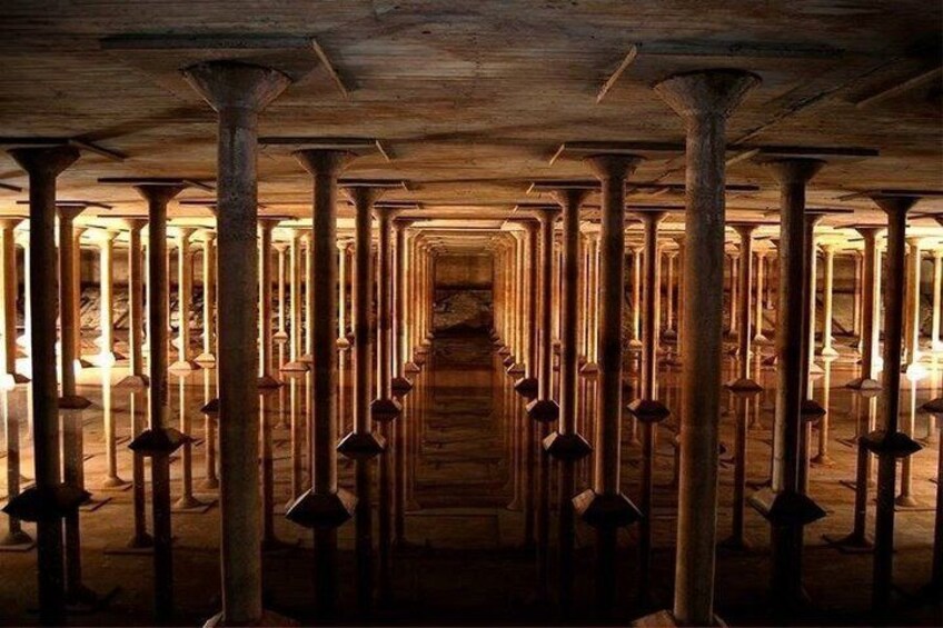 A dimly lit, narrow corridor with wooden beams and columns, leading to a central wooden door. 3