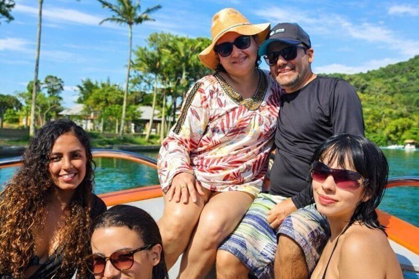 A group of people on a boat with a tropical landscape in the background. 3