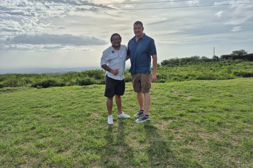 Two people standing in a grassy field with a cloudy sky in the background. 2