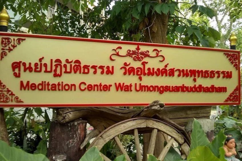 A sign for a Meditation Center Wat Umongsuabuddham with a decorative cart structure. 2
