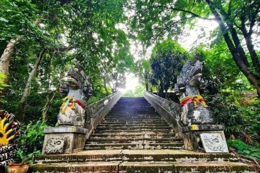 A staircase leading up to a temple entrance, surrounded by lush greenery and stone statues. 3