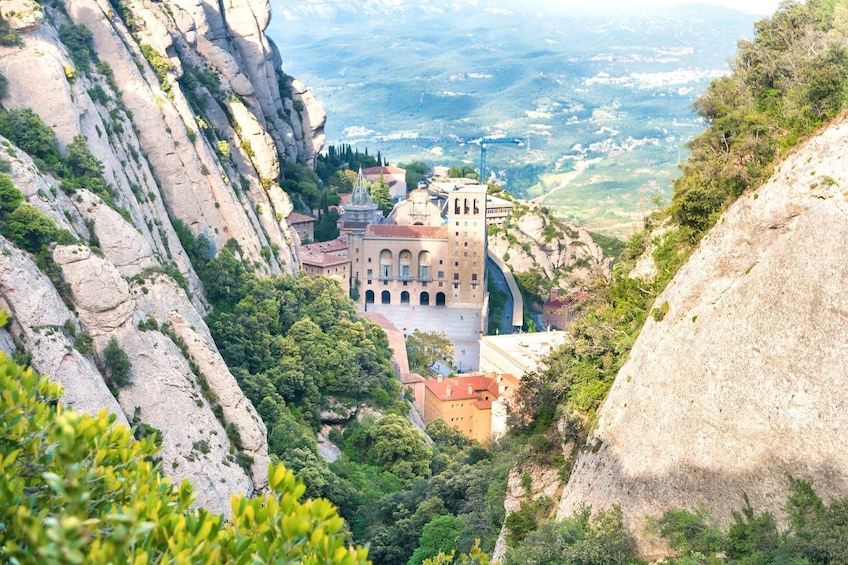 A historic building with arched windows and a bell tower, surrounded by rocky cliffs and lush greenery. 5