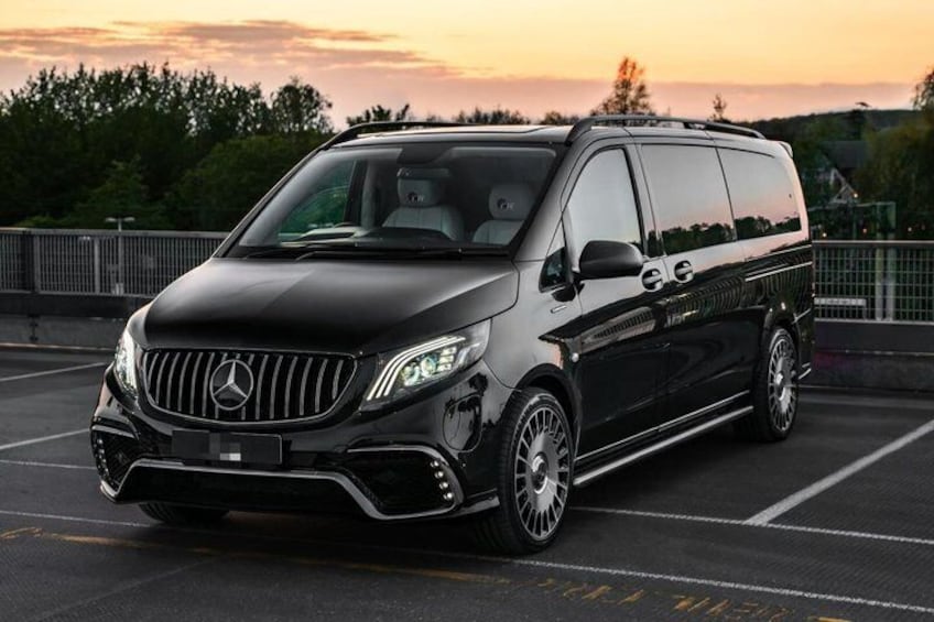 A black Mercedes-Benz Sprinter van parked in a parking lot during sunset. 2