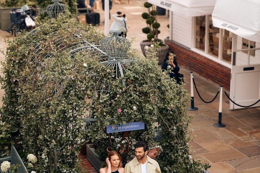 A garden with a metal structure, a sign reading 'Sont esperance,' and a building in the background. 3
