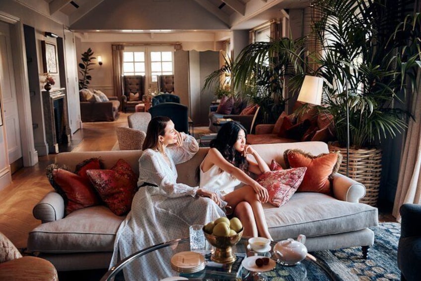 A cozy living room with a sofa, cushions, a coffee table with a teapot, and a potted plant. 5