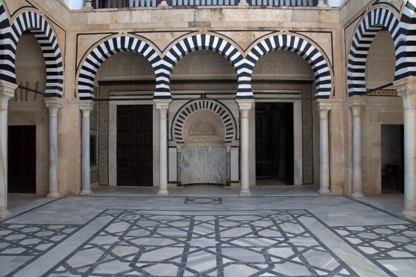 A courtyard with arches, a marble floor, and a central column. 3