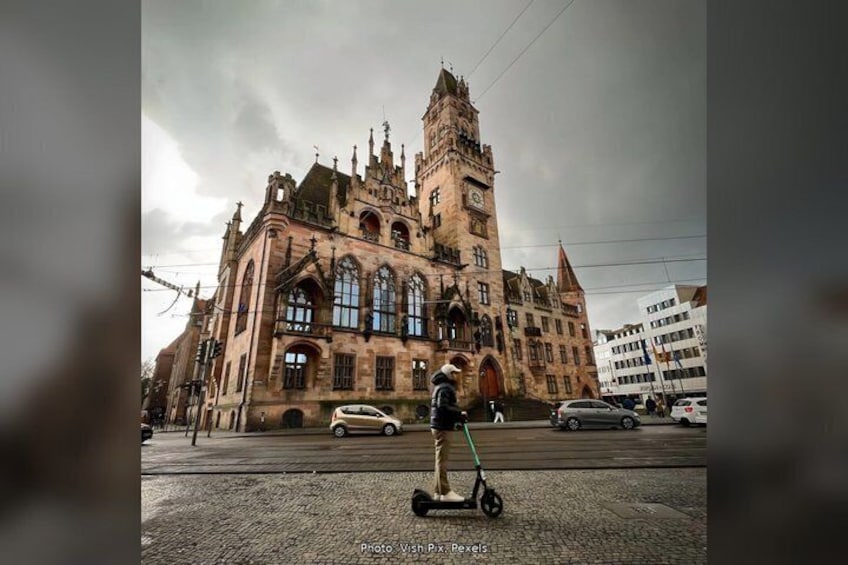 A person riding a Segway on a cobblestone street in front of a historic building with Gothic architecture. 5