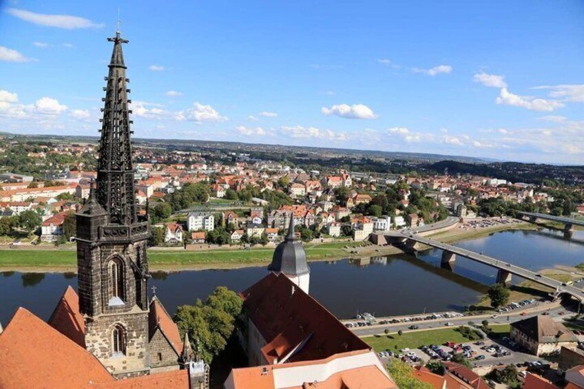 A town with a prominent church tower, a river, and a bridge. 2