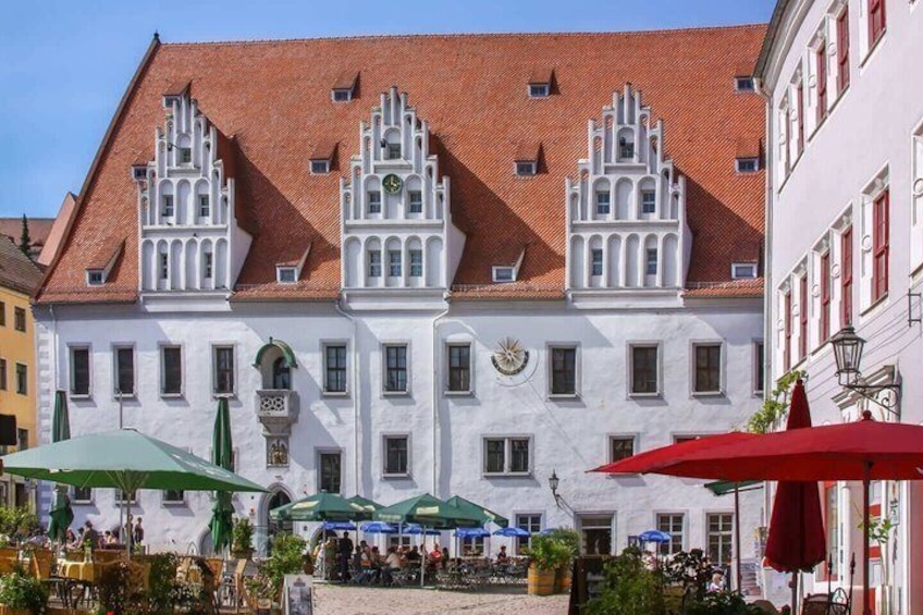 A historic building with ornate architecture, outdoor seating with umbrellas, and a clear blue sky. 3