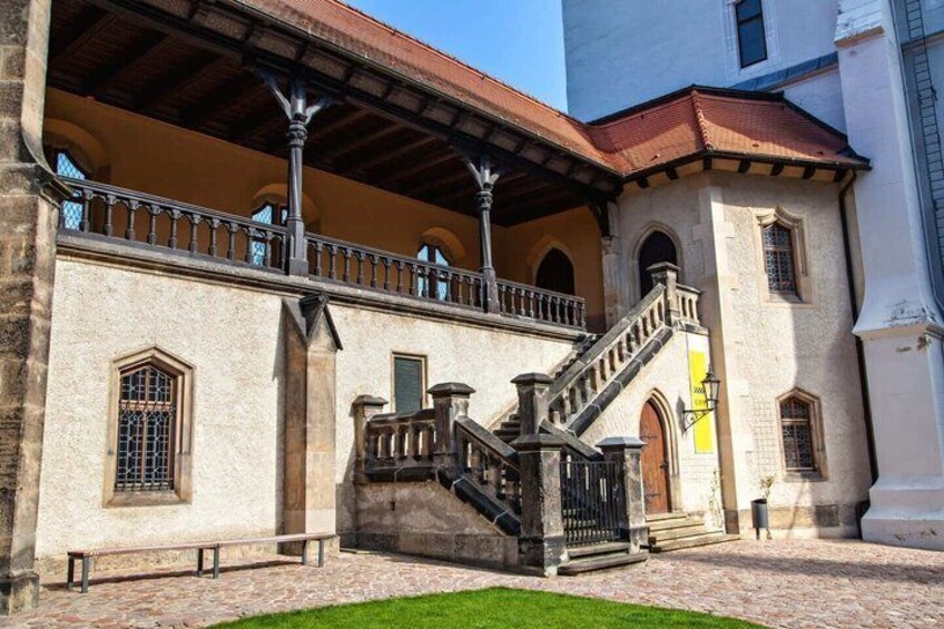A historic building with a stone facade, a balcony, and a staircase leading to the entrance. 5