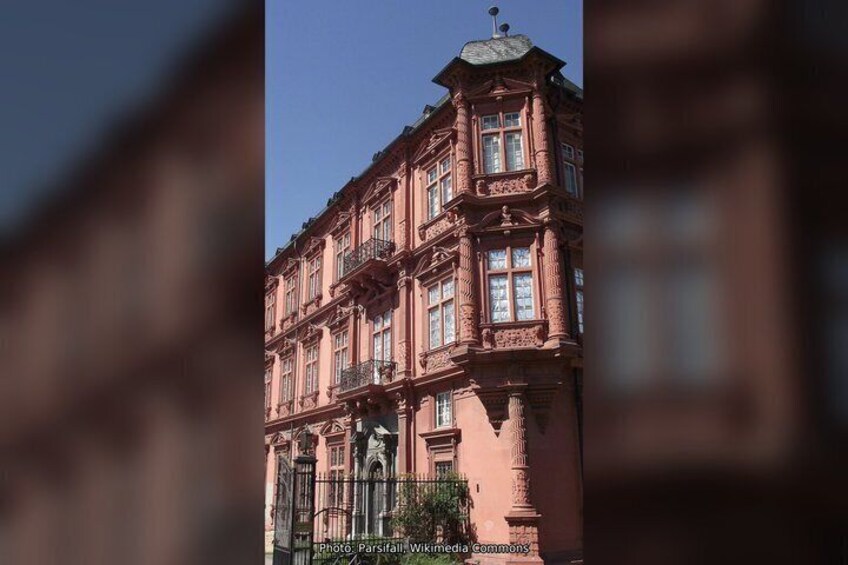 A pinkish-red building with ornate architectural details, including columns and a balcony. 3