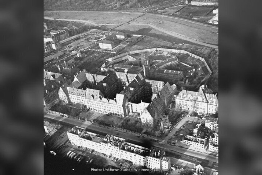 An aerial view of a historic town with a prominent castle, a river, and surrounding fields. 2