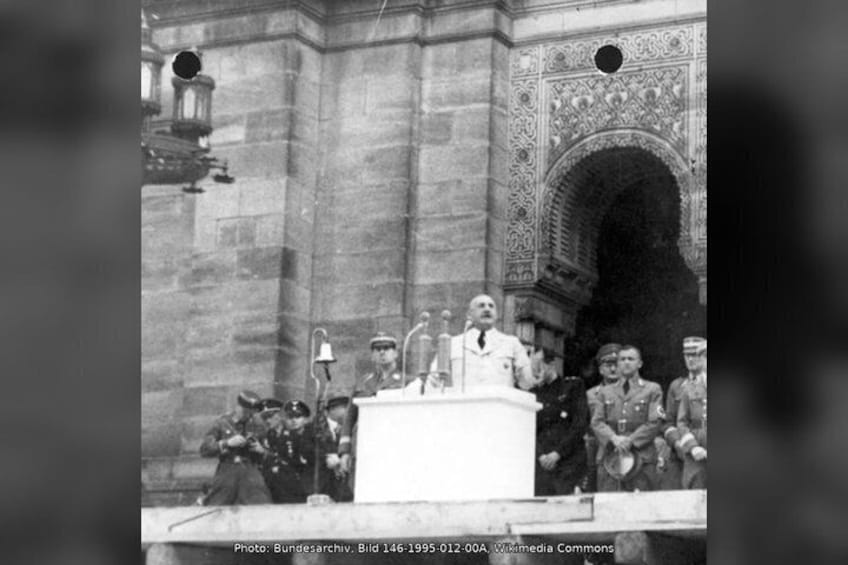A historical scene with a podium, a crowd, and ornate architecture. 4