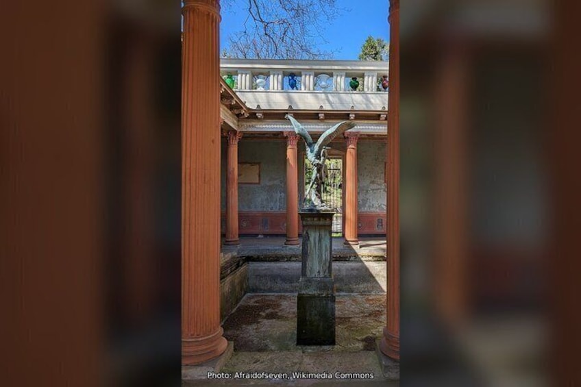 A courtyard with columns, a statue, and a building with a tiled roof. 3