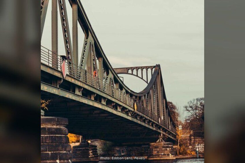A steel bridge with a curved arch over a river, supported by large concrete blocks. 2