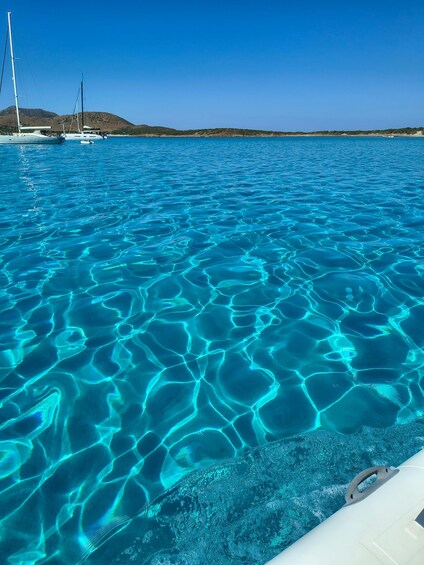 A clear blue sea with boats and a distant shoreline. 5