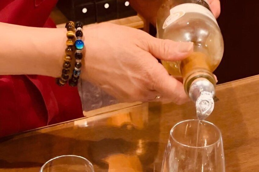A person pouring a clear liquid from a bottle into a glass. 4