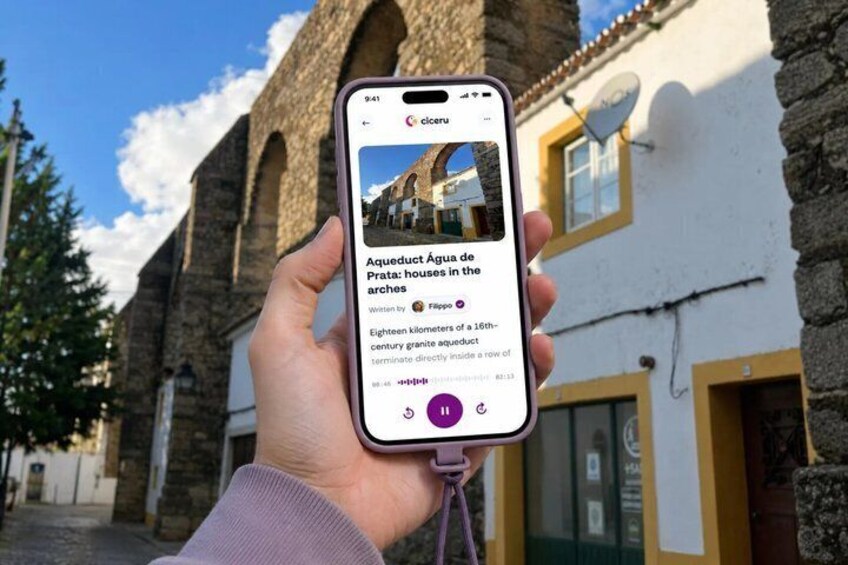 A hand holding a smartphone displaying a photo of a historic building with arches. 1