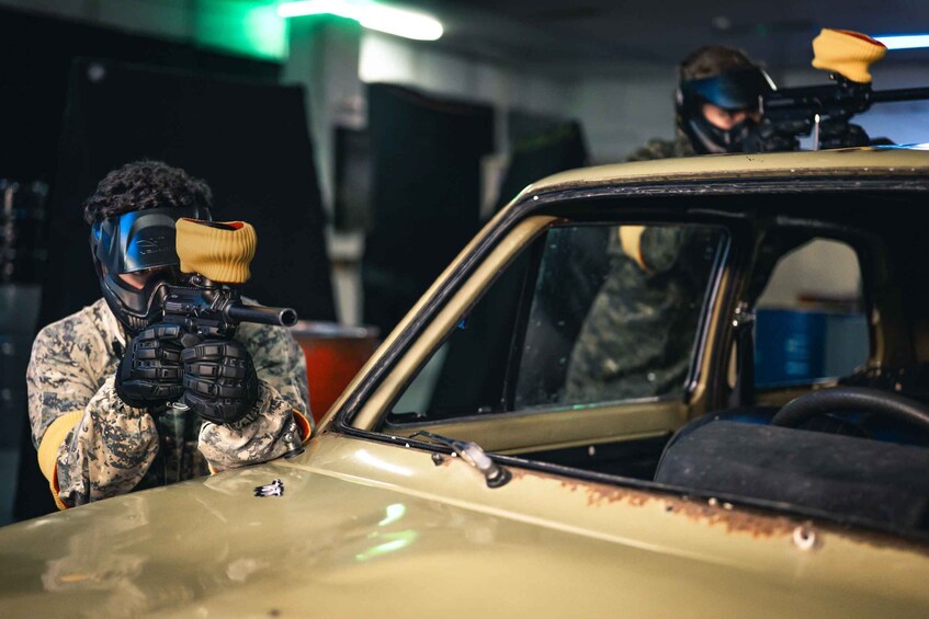 Two individuals in military camouflage gear aiming rifles at a vehicle. 4