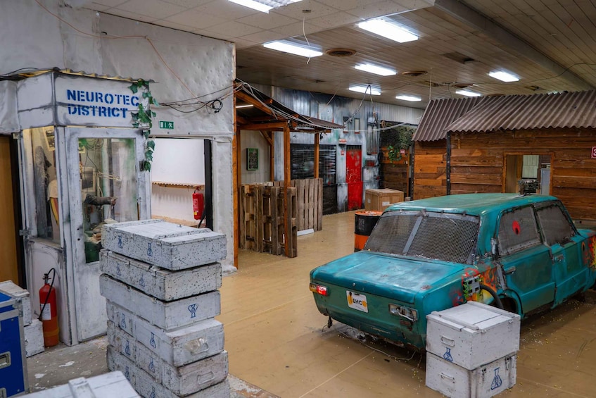 A workshop with a teal car undergoing repair, wooden crates, and a sign reading 'NEUROTEC DISTRICT'. 5