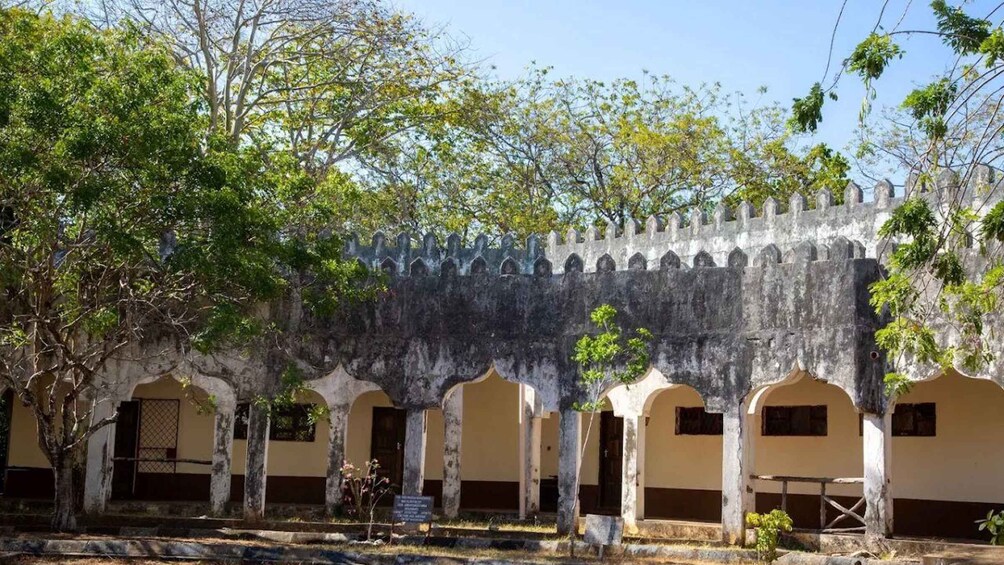 A historical building with arched doorways and a stone wall. 2