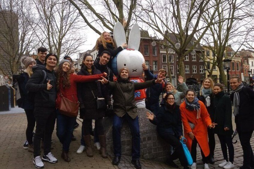 A group of people posing with a large rabbit statue in a city square. 1