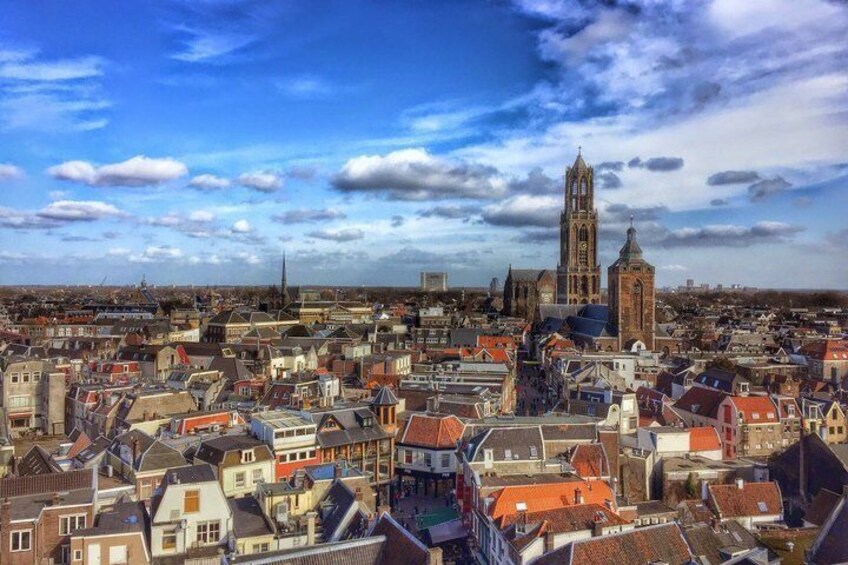 A cityscape with a prominent church tower, dense urban buildings, and a clear sky. 3