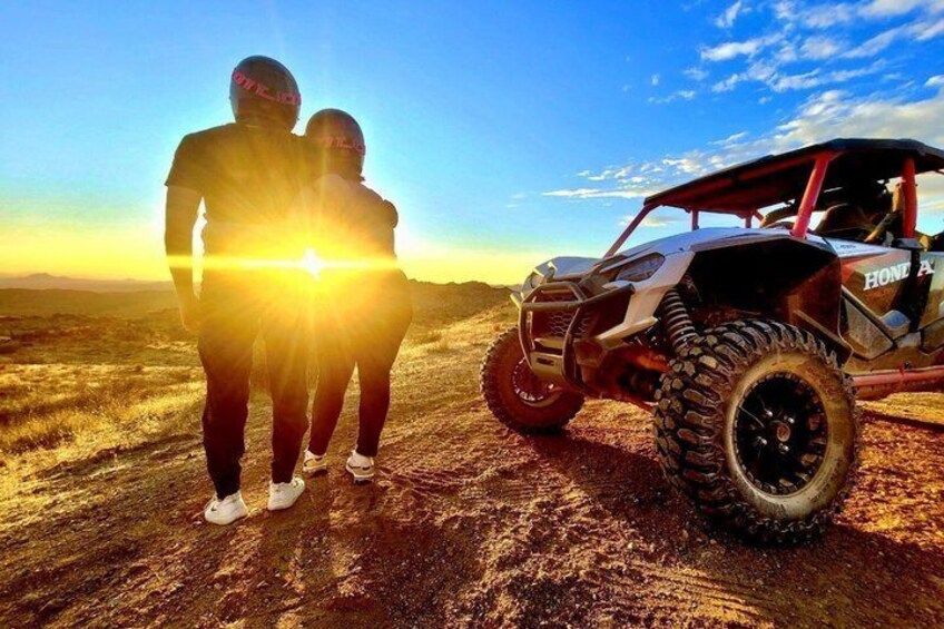 A couple standing in a field with a dune buggy parked nearby. 1