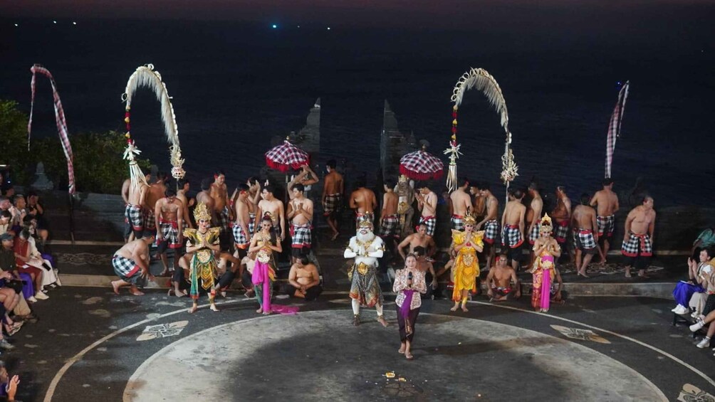 A nighttime outdoor cultural performance with participants in traditional attire, some carrying decorated umbrellas. 3